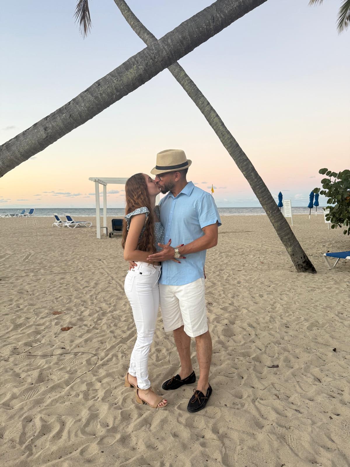 José Miguel y Amanda besándose bajo palmeras en la playa